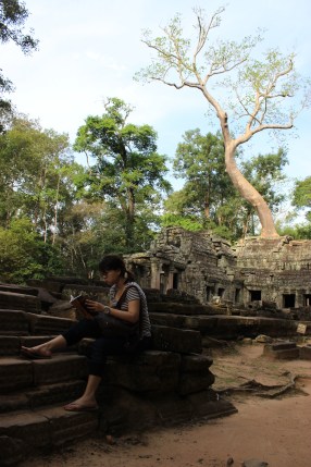 A tourist absorbs a book amidst this treasured jungle backdrop. 