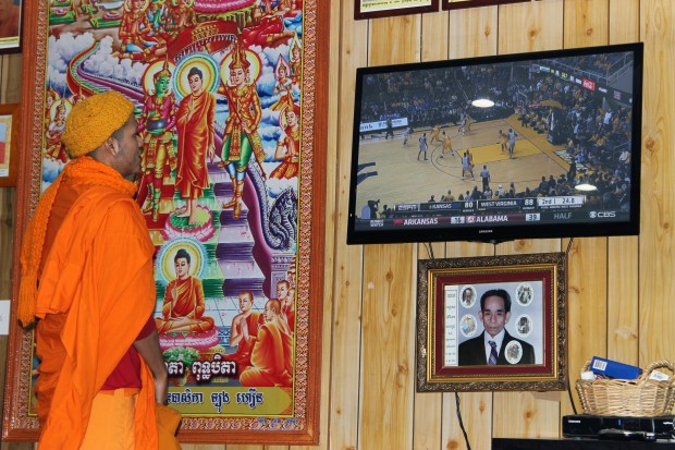 A young Cambodian monk watches a NCAA basketball game before prayers at Wat Jotanaram. 
